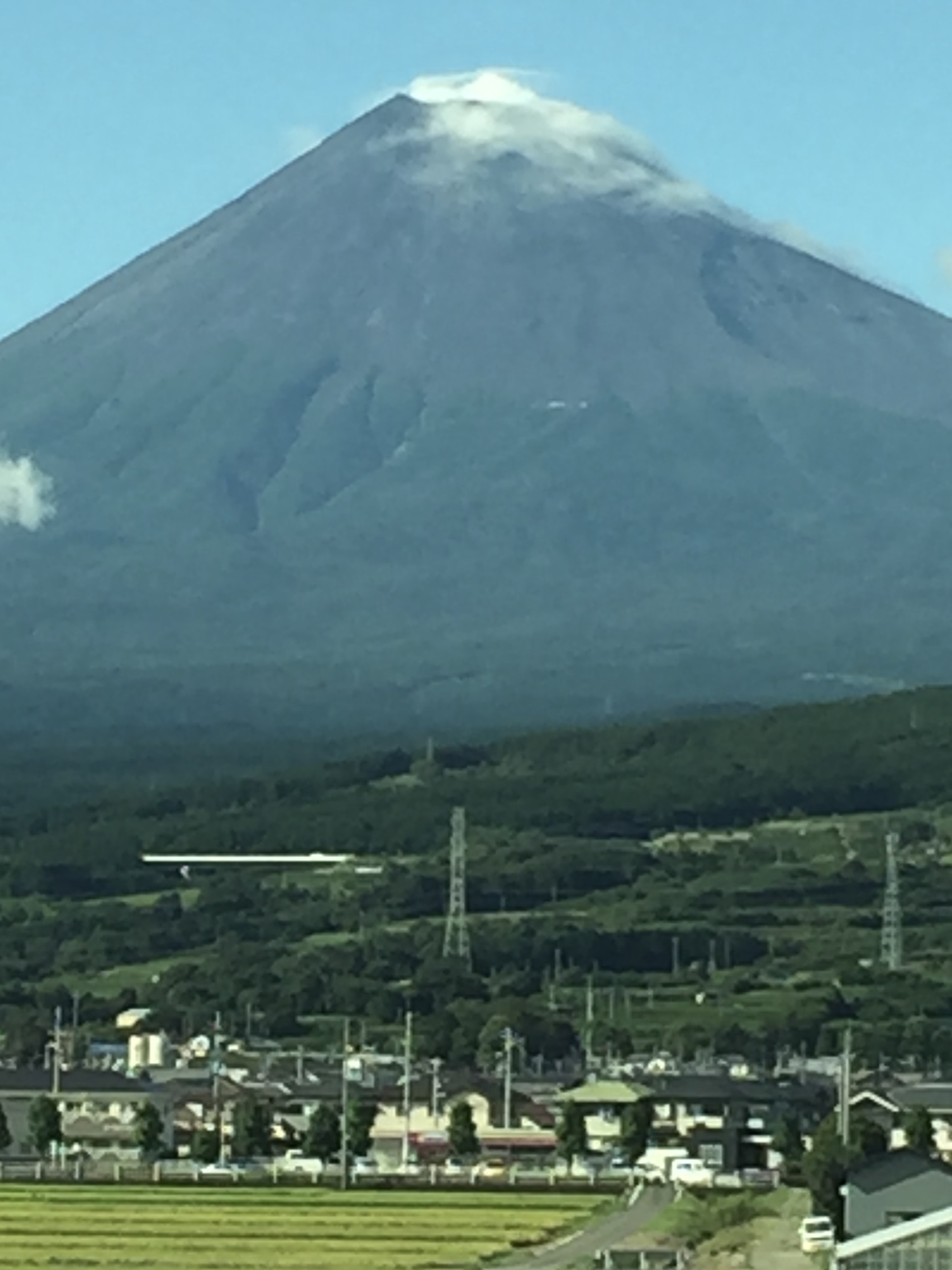 Departing the Mount Fuji region after our climb — a view from the train window, the summit rising quietly in the distance.